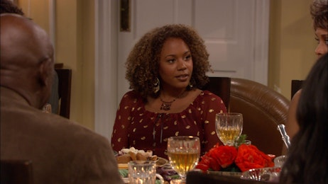 Rachel True in red top with white spots, sits at table with dinner and wine glasses