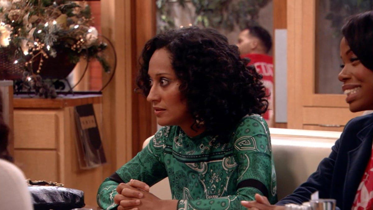 Joan from Girlfriends wears a green top in a booth in a cafe decorated for Christmas