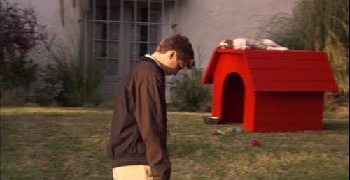 George Michael hangs his head like Charlie Brown. Red playhouse on the right.