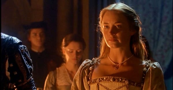 Emily Blunt as Catherine Howard with blonde hair in white period dress.