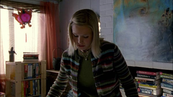 Veronica mars wears striped jacket in a bedroom full of books